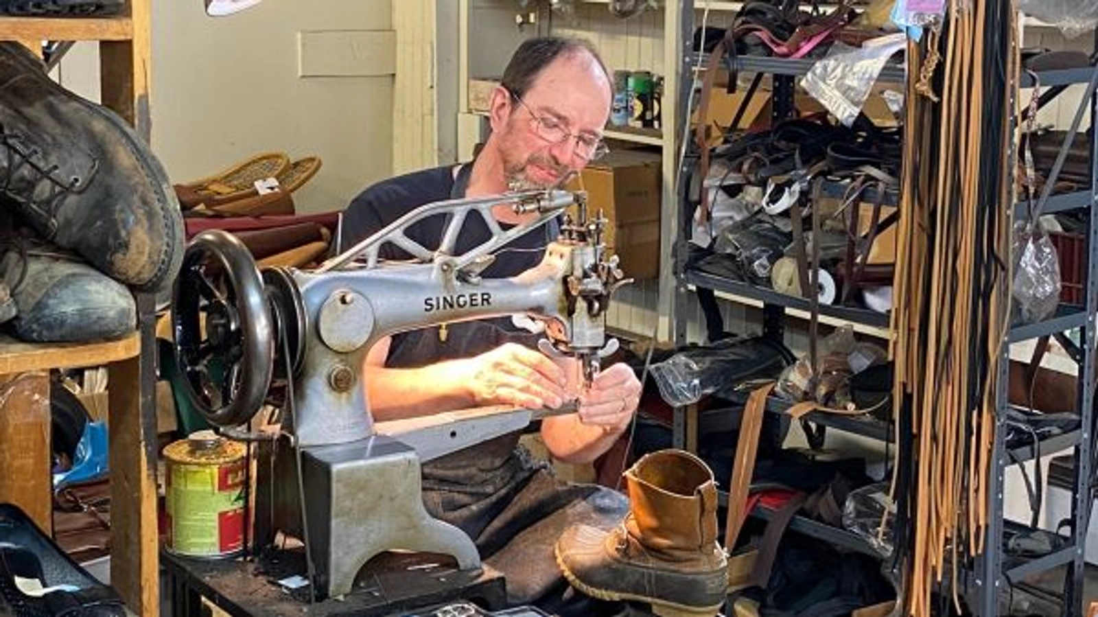 A craftsperson working at a leather sewing machine inside Tom Finn Shoe Repair